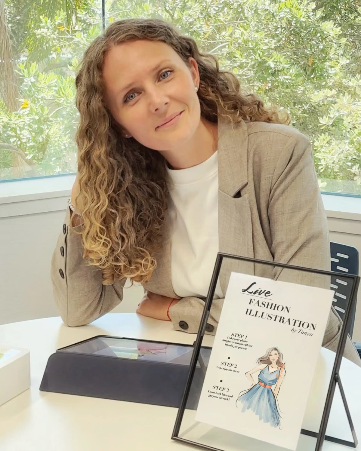 Revastique live event illustration artist in Auckland seated with a framed live fashion sketch
